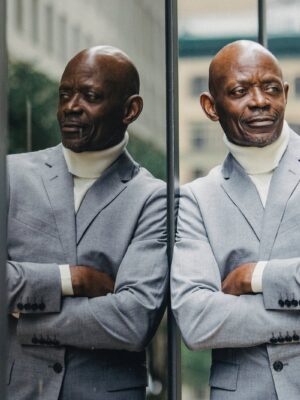 Confident black man leaning on glass building