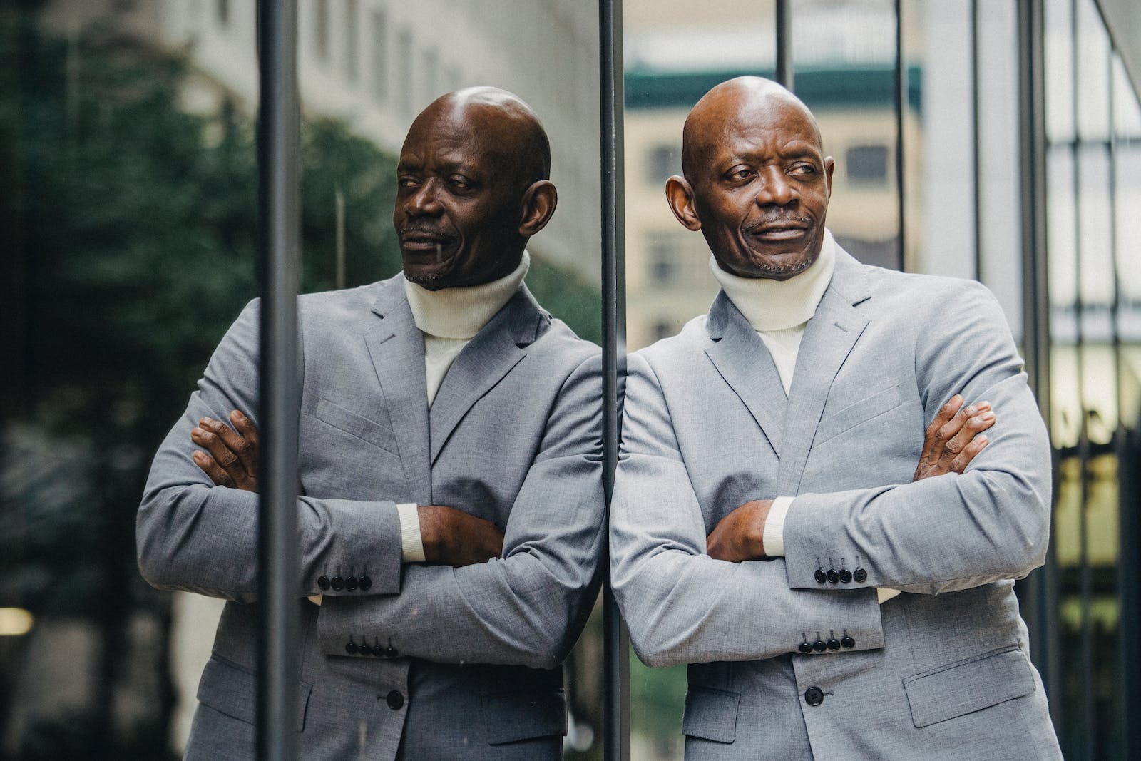 Confident black man leaning on glass building